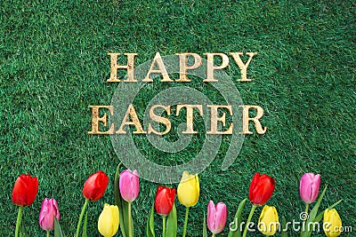 Happy Easter text on green grass with colorful tulips Stock Photo