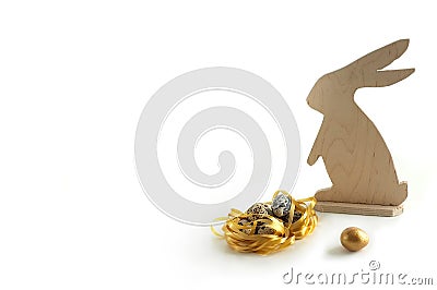 Happy easter. A wooden rabbit and quail eggs, a golden egg. Golden nest and golden egg. Small Eggs Stock Photo