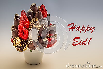 Happy Eid greeting card with red lettering; A bundle of edible flowers, arrangement of strawberries covered with chocolate Stock Photo