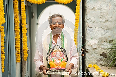 Happy Elder man with Ganesha Idol coming home during ganesha or vinayaka Chaturthi festival - Concept of indian Stock Photo
