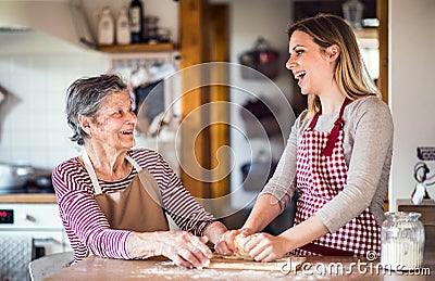 An elderly grandmother with an adult granddaughter at home, baking. Stock Photo