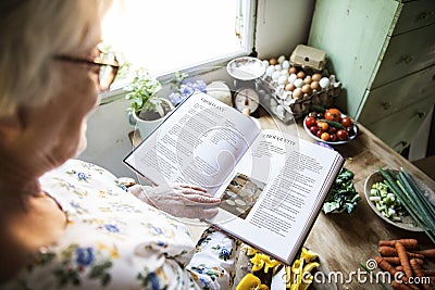 Happy elderly woman reading a cookbook Stock Photo