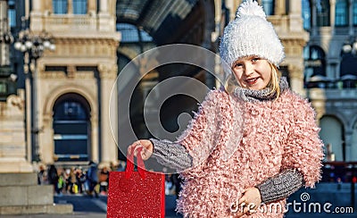 Happy elegant child showing red shopping bag in Milan, Italy Stock Photo