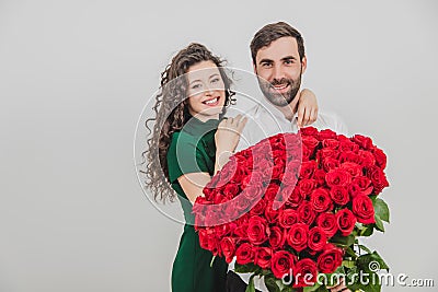 Happy elegant couple is hugging and smiling, on white background. Man is holding roses. Stock Photo