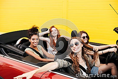 Happy emotional four young women friends sitting in car Stock Photo