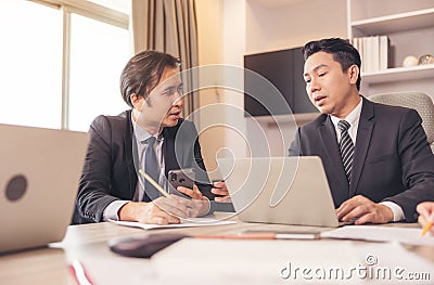 Happy employees discussing potential business Two knowledgeable business people working together with laptops while talking about Stock Photo