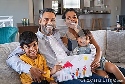 Happy ethnic family showing painting with new home Stock Photo