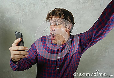 Happy and excited man celebrating success making money online gambling with mobile phone winning internet bet isolated grunge Stock Photo