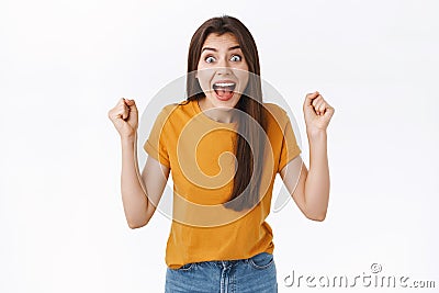 Happy, excited and relieved young woman heart amazing news, fist pump, raise clenched hands in joy and amazement, stare Stock Photo