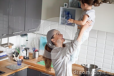Happy smiling mum holding daughter in kitchen Stock Photo
