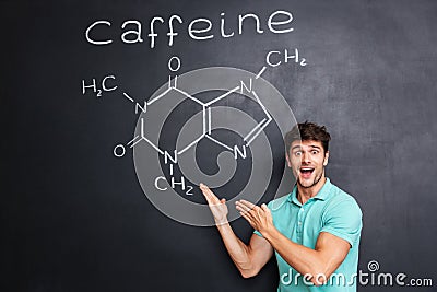 Happy excited young scientist showing chemical structure of caffeine molecule Stock Photo