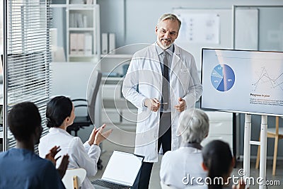 Happy experienced clinician in lab coat standing in front of audience Stock Photo