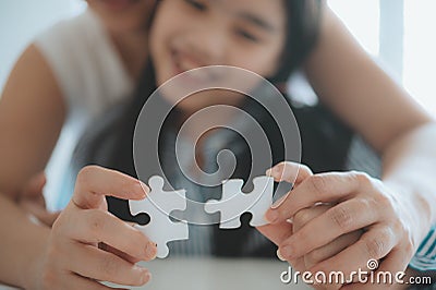 Happy family, Asian daughter playing jigsaw puzzle with her mother for family concept, Adult woman teaches child to solve puzzles Stock Photo