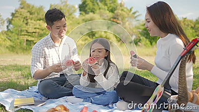 Happy family asian and little girl are eating watermelon and have enjoyed ourselves together during picnicking Stock Photo