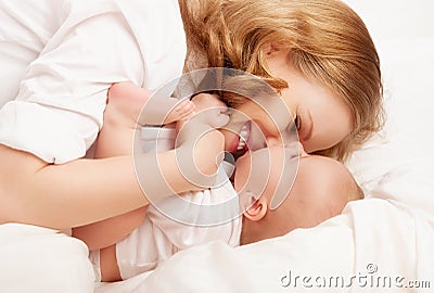 Happy family. baby and mother play, kiss, tickle, laugh in bed Stock Photo