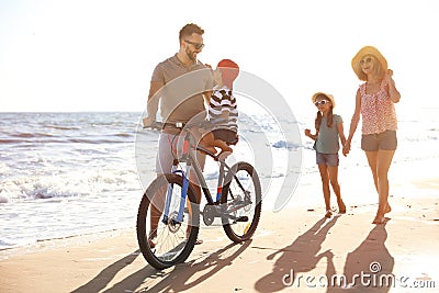 Family with bicycle on sandy beach near sea Stock Photo