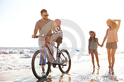 Happy family with bicycle on sandy beach Stock Photo