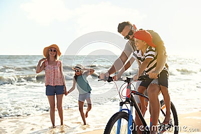 Happy family with bicycle on sandy beach near sea Stock Photo