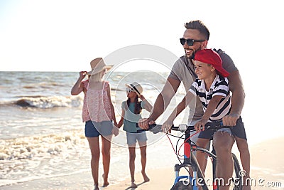 Happy family with bicycle on sandy beach near sea Stock Photo