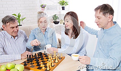 Happy family chess game time at nursing home for elderly. Parents with children have fun talk and leisure. Senior couple Stock Photo