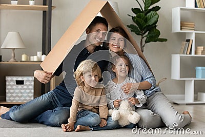 Happy family couple and two skids holding cardboard roof overhead Stock Photo
