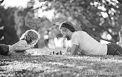 happy family of daddy and son child playing chess on green grass in park outdoor, erudite Stock Photo