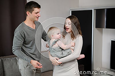 Happy family dancing in the living room holding a toddler in their arms. Concept of hobbies, having fun with children Stock Photo