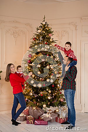 Happy family decorate the Christmas tree indoors together. Loving family. Merry Christmas and Happy Holidays Stock Photo