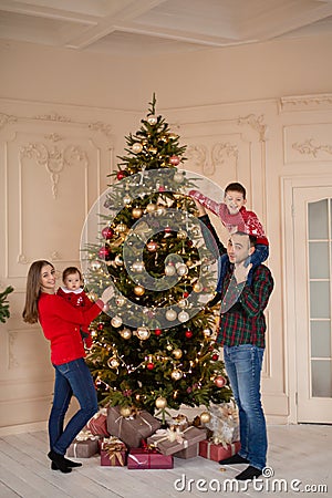 Happy family decorate the Christmas tree indoors together. Loving family. Merry Christmas and Happy Holidays Stock Photo