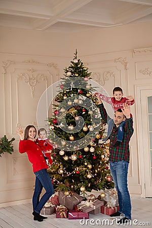 Happy family decorate the Christmas tree indoors together. Loving family. Merry Christmas and Happy Holidays Stock Photo