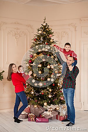 Happy family decorate the Christmas tree indoors together. Loving family. Merry Christmas and Happy Holidays Stock Photo