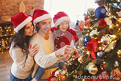 Happy family decorating Christmas tree with bubbles in living room Stock Photo