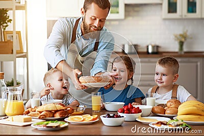 Happy family father with children feeds his sons and daughter in kitchen with Breakfast Stock Photo