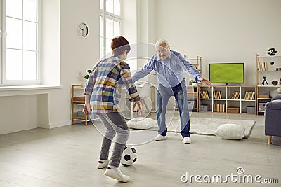 Elderly grandfather playing football with grandson in home living room Stock Photo