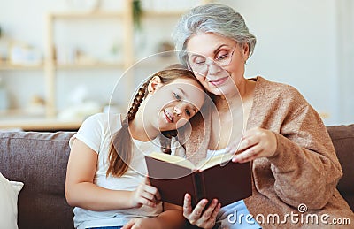 Happy family grandmother reading to granddaughter book at home Stock Photo