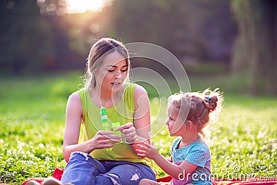 Happy family having fun- child blows soup foam and make bubbles with her mother in nature Stock Photo