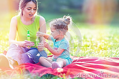 Happy family having fun- Female child blows soup foam and make bubbles in nature Stock Photo