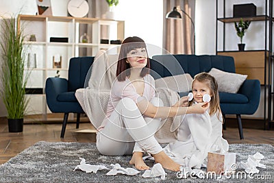 Happy family having fun together after bath. Young mother sitting with her little daughter on gray carpet in cozy living Stock Photo