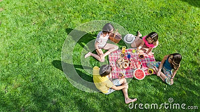 Happy family having picnic in park, parents with kids sitting on grass and eating healthy meals outdoors Stock Photo