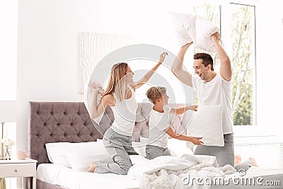 Happy family having pillow fight on bed Stock Photo