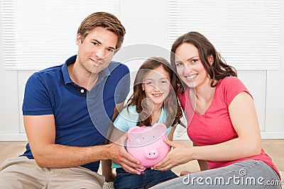 Happy family holding piggy bank at home Stock Photo