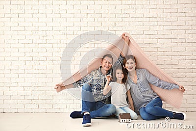 Happy family with house model and key of their new home under plaid indoors Stock Photo