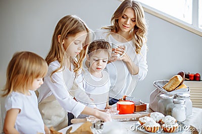 Happy family in the kitchen. Mother and her cute kids are cooking cookies. Stock Photo