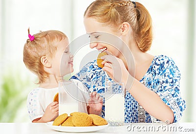 Happy family mother and baby daughter girl at breakfast: biscuits with milk Stock Photo