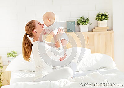 Happy family mother with baby playing and hug in bed Stock Photo