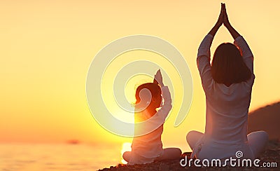 Happy family mother and child doing yoga, meditate in lotus position on beach Stock Photo