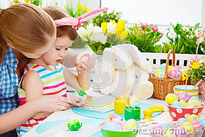 Happy family mother and child girl paints eggs for Easter Stock Photo