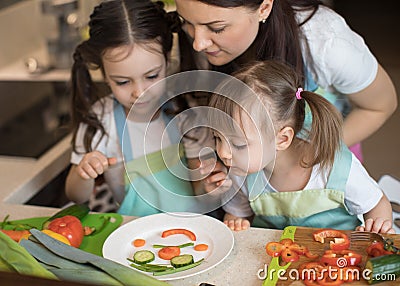 Happy family mother and child girl are preparing healthy food, they improvise together in the kitchen Stock Photo