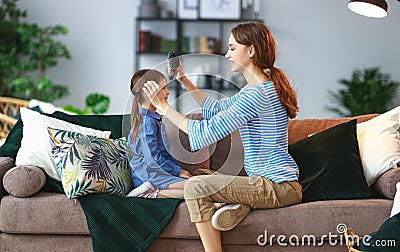Happy family mother and child play at home and sing with combs Stock Photo