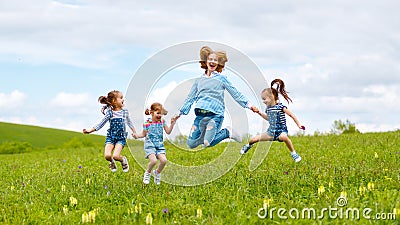 Happy family mother and children daughter girls laughing and jump on meadow in summer Stock Photo